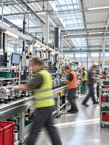 Workers in motion on a bright manufacturing assembly line